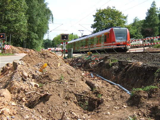 Bild: Ein Graben, ein Wall auf dem alten Weg, ein Bahnübergang und eine S-Bahn