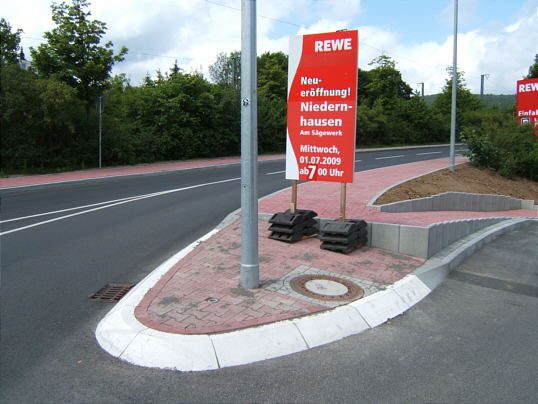 Bild: Der bizarre Bürgersteig und das Eröffnungs-Hinweis-Schild.